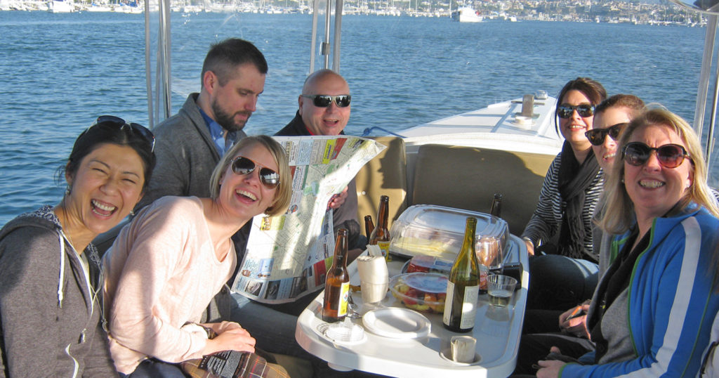 Happy boaters engaging in team offsite fun in Newport Harbor